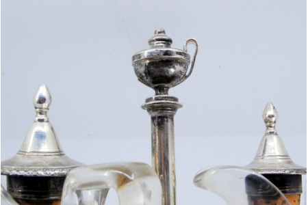  Galheteiro com estrutura em prata recortada em forma de nave com duas galhetas em vidro lapidado, assente sobre quatro pés relevados  e suporte para as tampas em prata.
