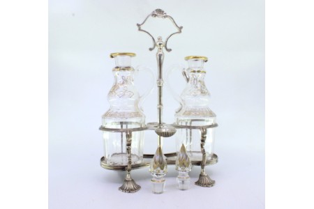 Galheteiro com estrutura em prata com duas galhetas em vidro lapidado e decoração com dourados.