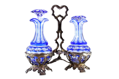 Galheteiro com estrutura em prata recortada com duas galhetas em vidro lapidado em tons de azul .