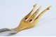 .Garfo de servir acepipes em prata com três dentes dourados e frisos ao longo do cabo.