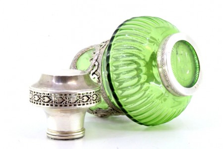 Garrafa licoreira em vidro verde relevado com aplicações e tampa em prata assente em base circular com frisos.