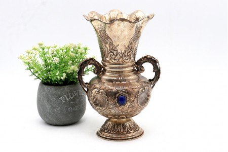 Jarra em prata com relevos e aplicações de conchas, duas pegas relevadas, dois cabochões azuis, bordo ondulado e base circular com frisos.