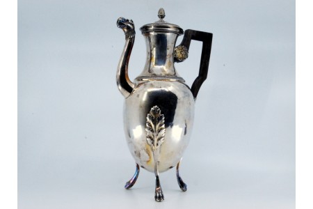 Chaleira em prata de corpo liso com frisos na tampa e rebordo, palmas, de forma trípode, bico em forma de cabeça de animal e cabo de madeira.
