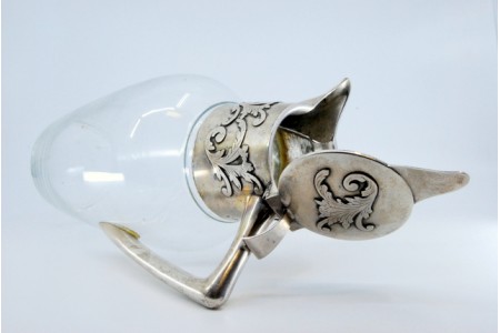 Jarro em vidro com gargalo e tampa em prata com aplicação.