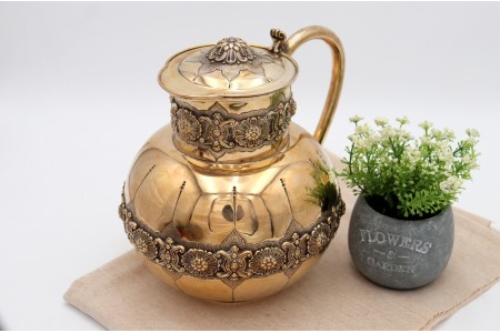  Jarro bojudo em prata dourada com relevos na tampa basculante e gomos sobre cintura relevada.