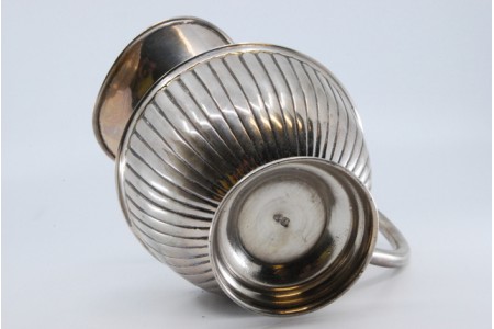 Jarro de água em prata  canelada, bojo largo e assente sobre base circular.