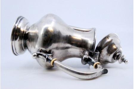 Cafeteira em prata lisa com pomo na tampa e assente sobre base redonda.