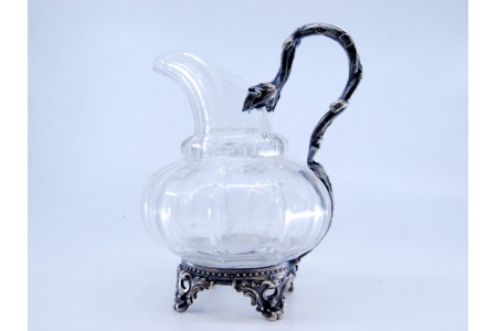 Jarro de água em vidro lapidado assente em estrutura de prata com quatro pés.