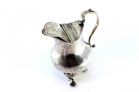  Leiteira em prata com relevos florais pega com aplicação e assente em três pés 