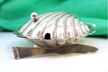 Manteigueira de prata em forma de concha gomada com faca relevada.