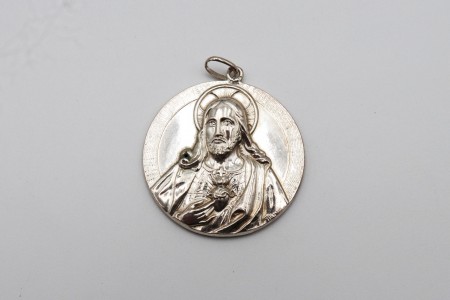 Medalha de prata com representação do Sagrado Coração de Jesus em alto relevo