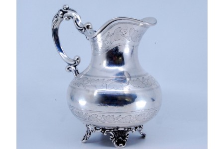 Jarro de água em prata com motivos vegetalistas gravados com pega e quatro pés relevados.