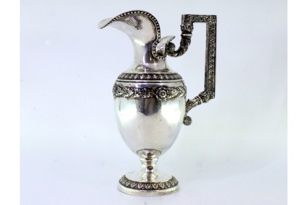 Jarro de água em prata com motivos florais relevados e frisos na envolvência.
