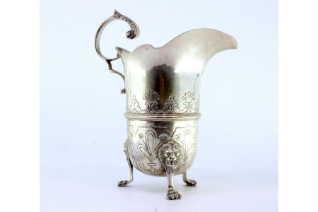 Cremeira em prata com motivos florais gravados, asa vazada em forma de folha de acanto e três pés alteados com cabeças de leões