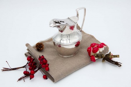 Leiteira em prata lisa com frisos envolventes e aplicação de motivos florais na tampa como pomo.