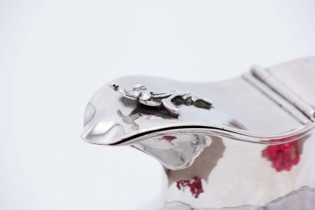 Leiteira em prata lisa com frisos envolventes e aplicação de motivos florais na tampa como pomo.