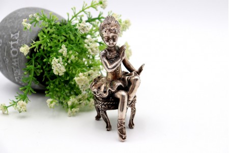 Miniatura de bailarina em prata com relevos e aplicações sentado em banco