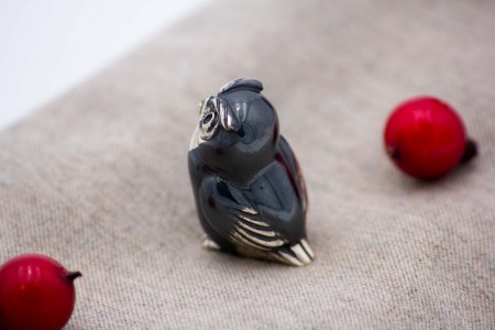 Miniatura de coruja em prata nielada em posição sentada.