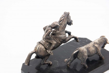 Campino montado a cavalo conduzindo touro em prata sobre base em mármore