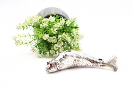 Peixe articulado em prata relevada com pedras vermelhas nos olhos.