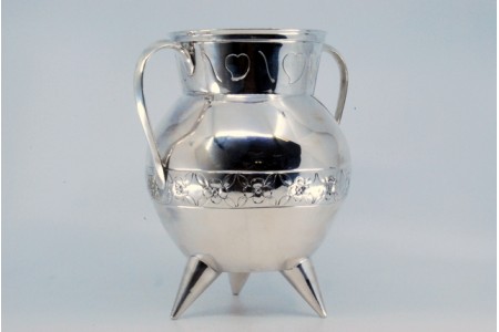 Pote em prata com motivos florais gravados e assente sobre três pés.