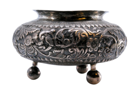 Pote em prata com relevos de grinaldas e motivos florais, assente sobre três pés esféricos.