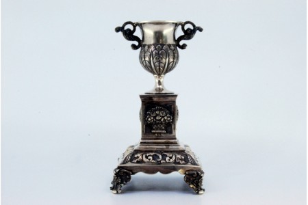 Paliteiro em prata com taça sobre pedrestal com motivos florais em base quadrada com quatro pés.
