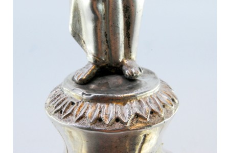 Paliteiro em prata com senhora em pedestal segurando taça e assente em base relevada sobre três pés.