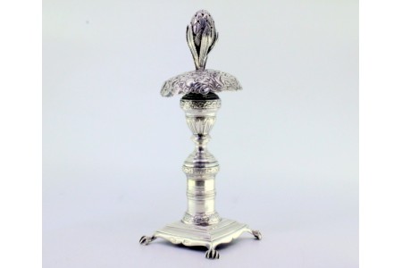 Paliteiro de prata cinzelada com fruto entre as folhas, sustido por cúpula 