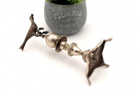 Paliteiro de prata com ave em poiso sobre ramos com folhas