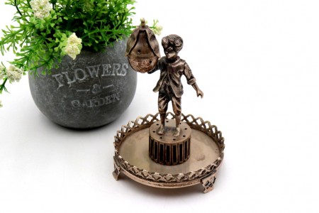 Paliteiro em prata com rapaz em pedestal segurando uma pera na mão 