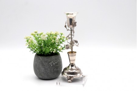  Paliteiro em prata com cálice sobre aplicações de trepadeira com folhas de acanto em base circular com gravados e três pés recortados.