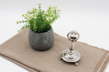 Paliteiro em prata em forma de morango assente em base circular adornada com motivos vegetalistas e três pés em forma de garras.