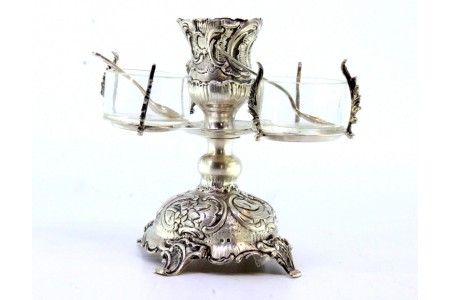 Castiçal em prata relevada com saleiro e pimenteiro em vidro, com colheres e assente em quatro pés com enrolamentos