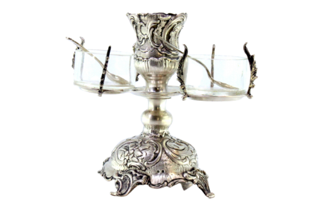Castiçal em prata relevada com saleiro e pimenteiro em vidro, com colheres e assente em quatro pés com enrolamentos