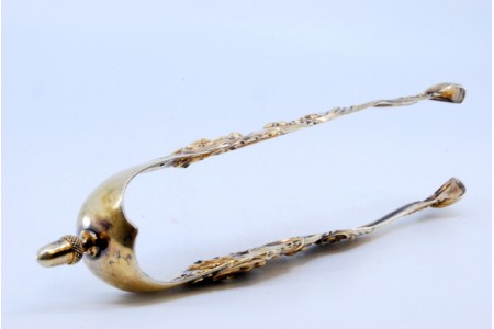 Pinça de açúcar em prata com relevos dourados e aplicações.