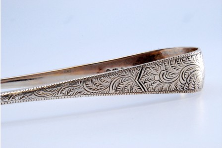 Pinça de açúcar em prata com motivos vegetalistas gravados.