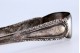 Pinça para gelo em prata em forma de garras com relevos.
