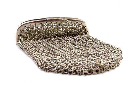 Bolsa porta moedas em malha de prata com duas divisórias e pingente em forma de bola recortada.