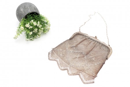 Bolsa em malha de prata com padrões decorativos, cadilhes suspensos e corrente