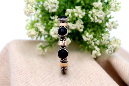 Pulseira em prata e ouro em formato retorcido e três cabochões negros.