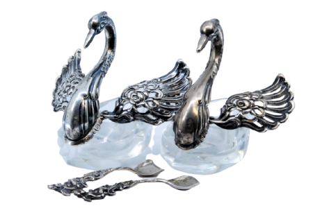 Saleiro e pimenteiro em vidro com figuras de cisnes de asas abertas em prata.
