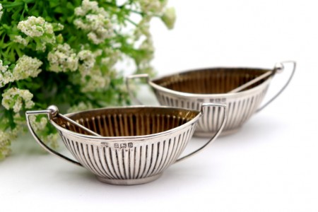 Conjunto de saleiro e pimenteiro em forma de navete com duas colheres.