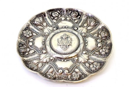 Salva de parede em prata com armas de Portugal relevadas e envolvidas por friso perlado e motivos florais.