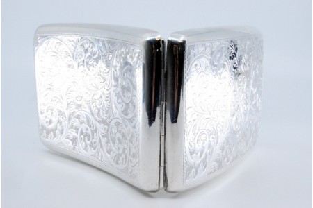  Cigarreira de prata com gravados em formato curvo e interior dourado com tampa basculante.