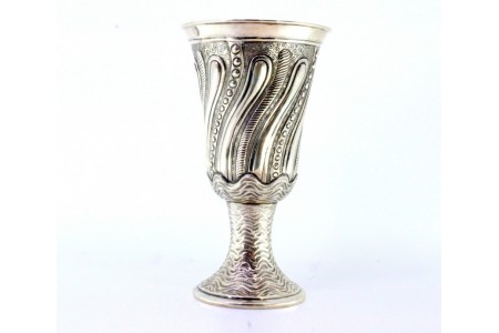 Taça em prata com relevos sobre base ondeada em forma circular.