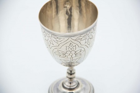 Taça de prata de base circular com motivos florais relevados.