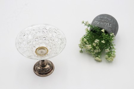 Taça de cristal lapidado com base em prata e motivos florais relevados com enchimento na base.