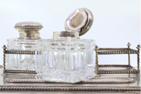 Tinteiro em prata com dois depósitos em vidro,  tampas em prata assente em base lisa e perlada com quatro pés relevados.