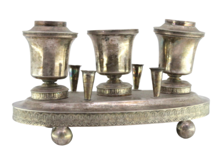 Tinteiro em prata com três depósitos, suportes para canetas com frisos guilhochados na envolvência e assente em quatro pés em forma de bolas.